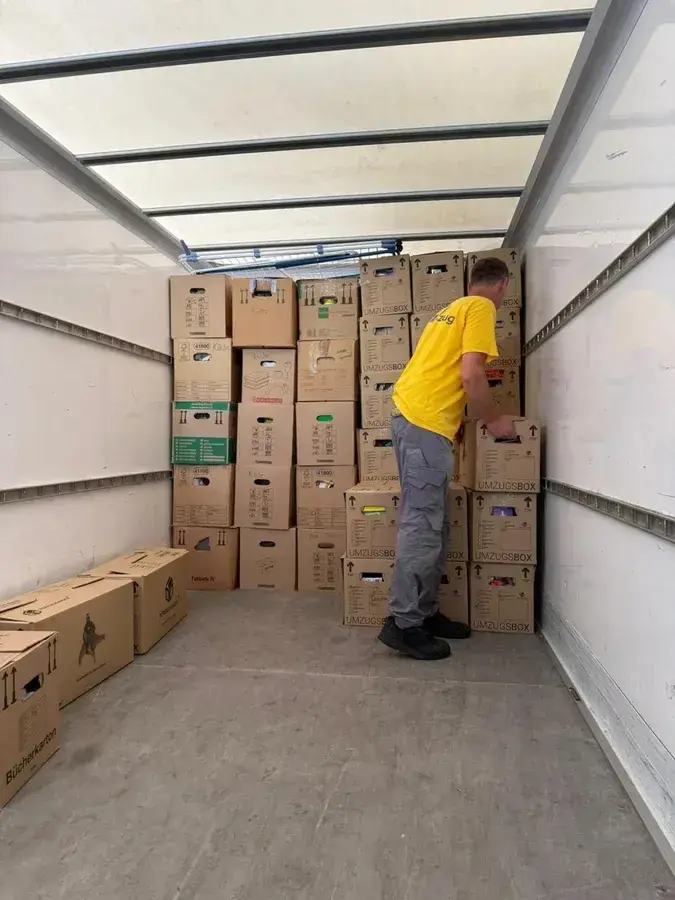 Umzugshelfer beim Beladen des LKW mit gestapelten Umzugskartons